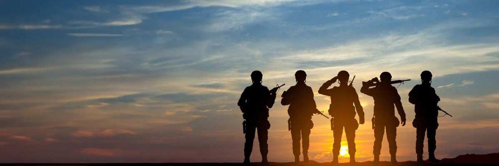 Silhouette of soldiers standing in front of sunset