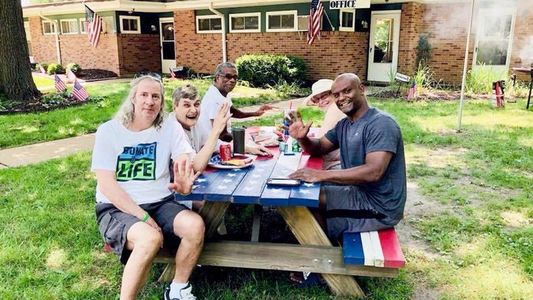 Group of veterans sitting at picnic table in front of the residence