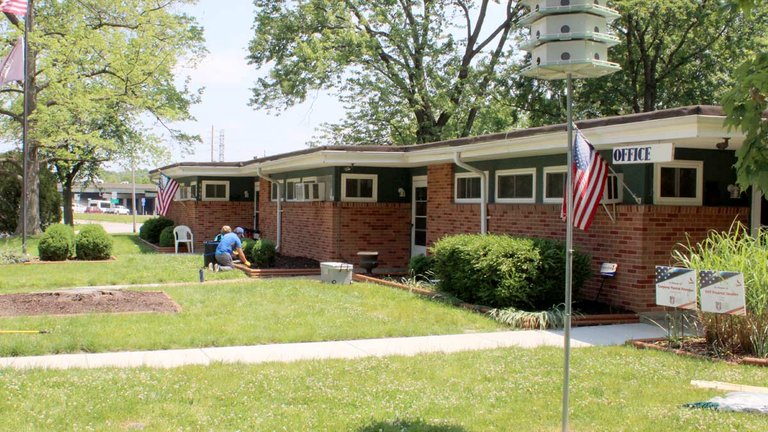 Two volunteers doing yard work in front of the the office