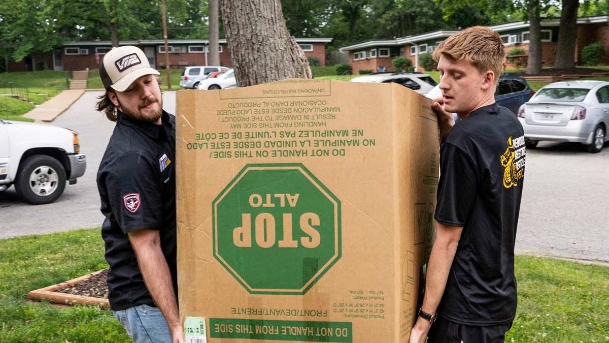 Two volunteers carrying a large box